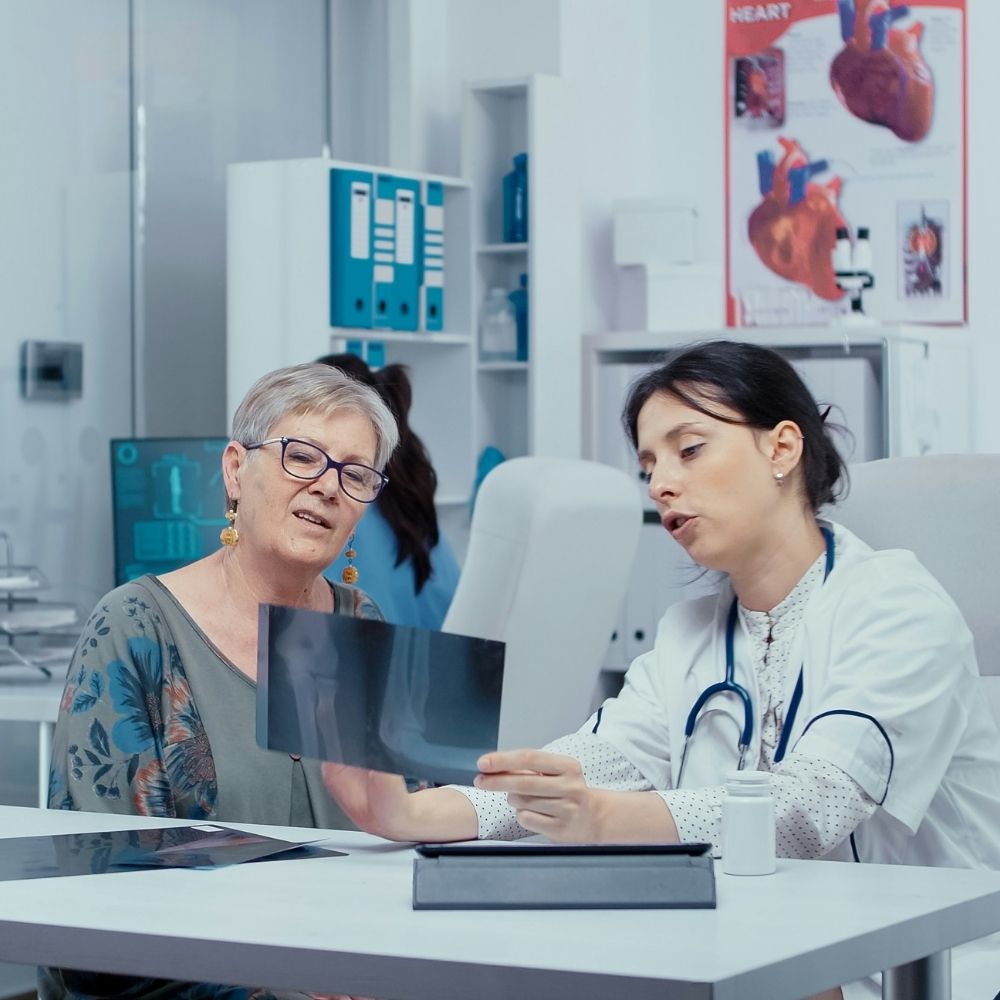 ASA (17) A doctor sits at a desk with a patient, reviewing an X-ray film together.