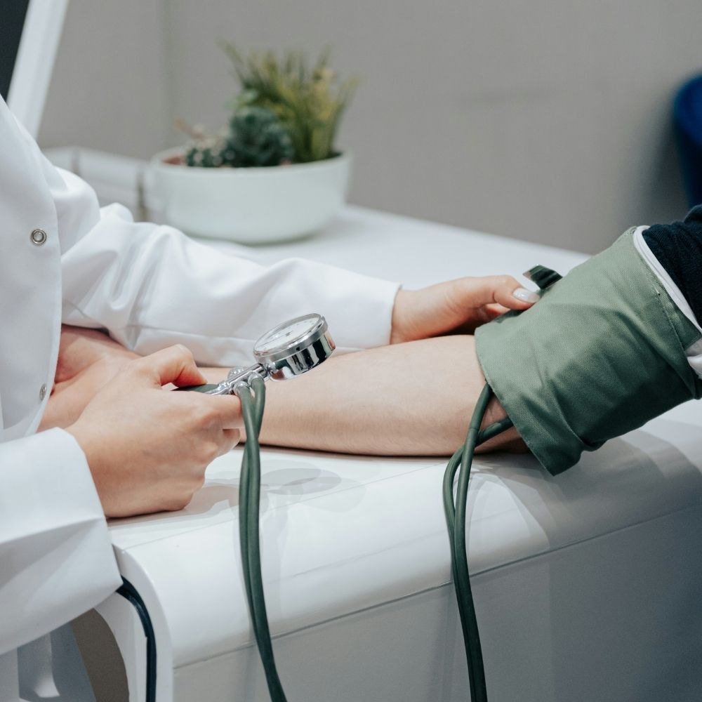 A healthcare professional taking a patients blood pressure with a manual cuff and gauge.
