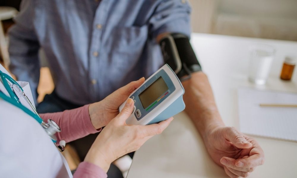 A healthcare professional checks a patients blood pressure using a digital monitor.